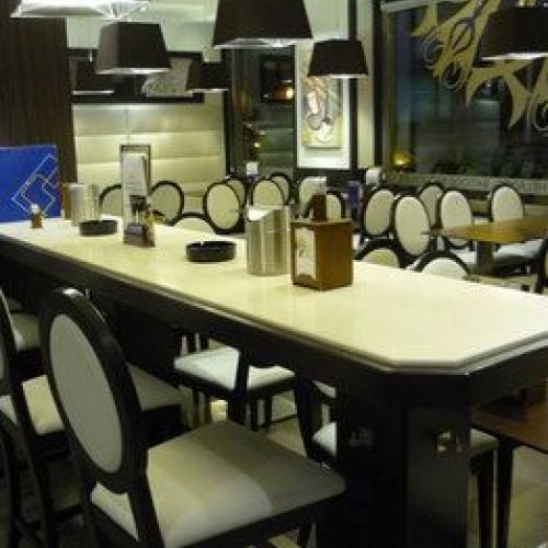 Interior de la cafetería con mesa y sillas altas