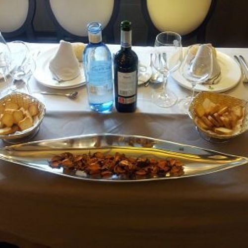 Detalle de mesa preparada con ración y botella de vino